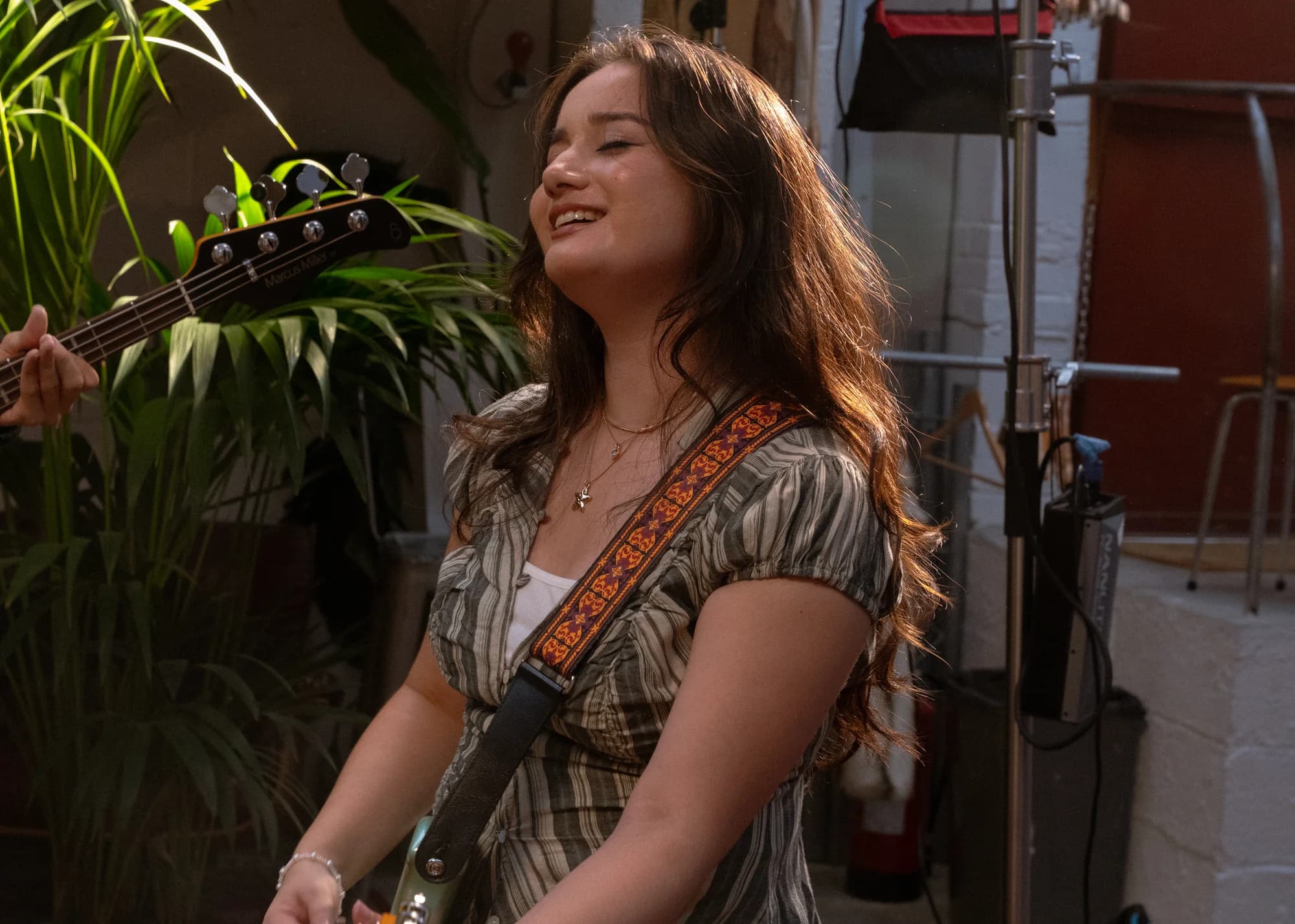 Clarissa Mae smiling with her electric guitar on the bed crumbs music video set at Bean World Studios