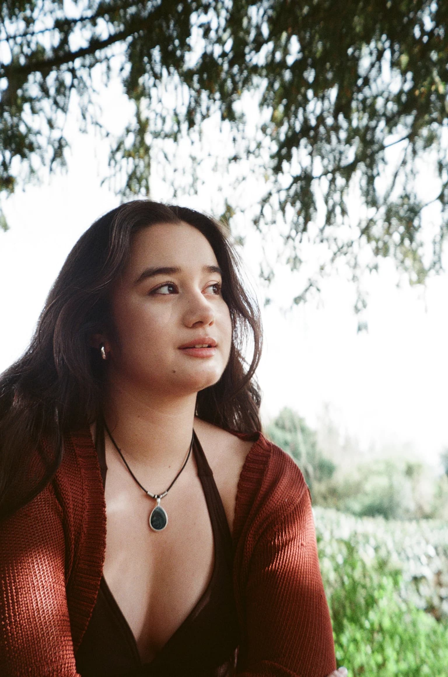 Clarissa Mae beneath overhanging branches in a sunlit outdoor portrait